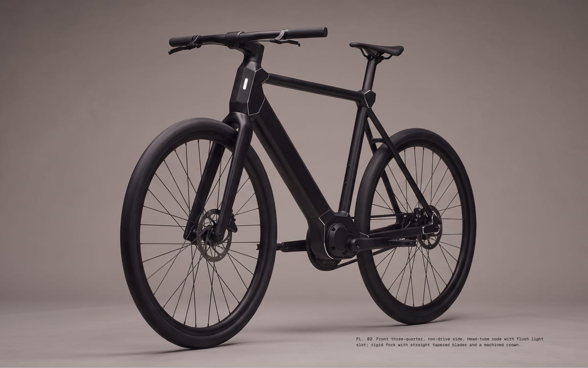 PL. 02 Front three-quarter, non-drive side. Head-tube node with flush light slot; rigid fork with straight tapered blades and a machined crown.